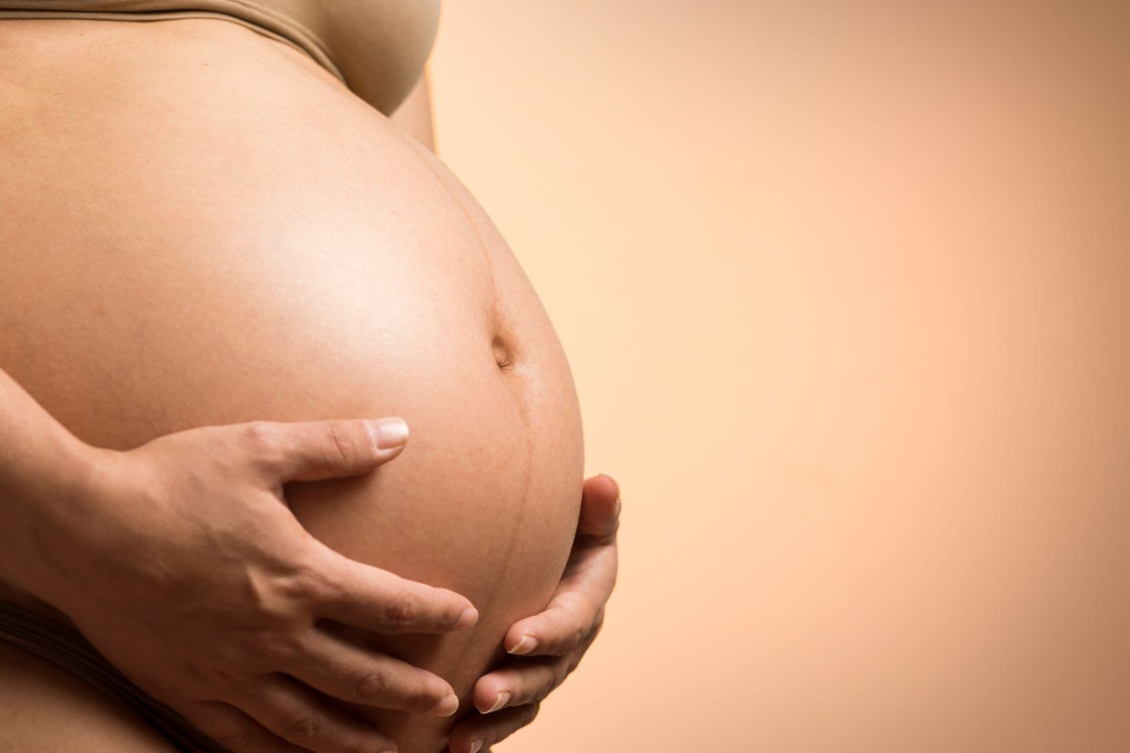 Les mains d'une femme enceinte posées sur son ventre